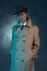 Mysterious retro 1940 asian gangster fashion man in raincoat.