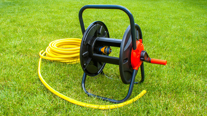 Naklejka premium Coiled rubber garden yellow hose on grass