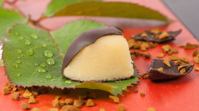 Marzipan orange chocolate candy on a green leaf