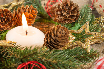 Christmas candle and ornaments: Christmas wreath, pine branches, pine cones, yellow glitter Christmas stars and Christmas balls