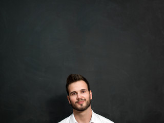 Portrait of a serious young man standing against chalkboard