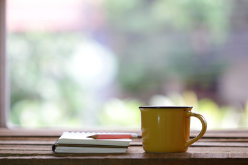 Notebook and yellow cup on wooden table