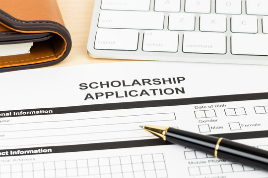 Scholarship application form with keyboard and pen - a person is shown in the image, and a person is