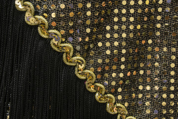 Detail of a 1920's flapper dress from the roaring twenties.  It has black fringe and shiny gold sequins.
