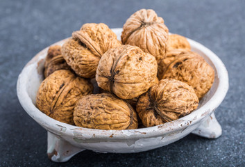 Walnuts in a white bowl on a black background