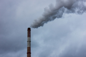 Pipe with smoke, gray sky and clouds