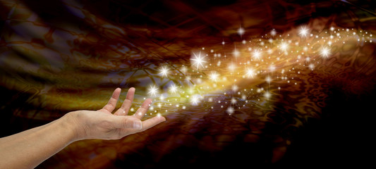 Creating Magic - Female open hand appearing to send out a stream of sparkles and glitter on a...