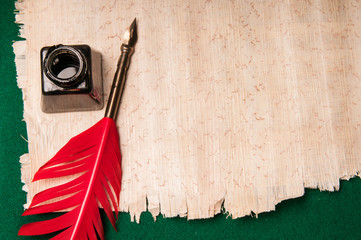 Red quill pen and black inkwell on a papyrus sheet