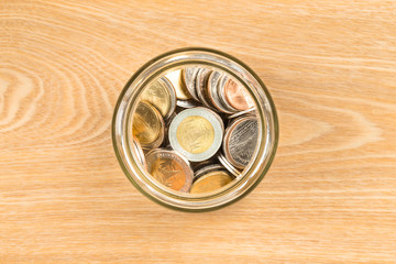 Coin jar on wooden desk top view