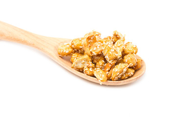 Crispy sugared nuts with wooden spoon isolated on white.