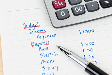 Hand writing home budget with calculator