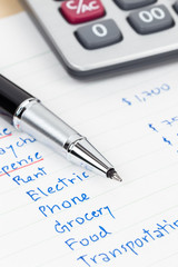 Hand writing home budget with calculator