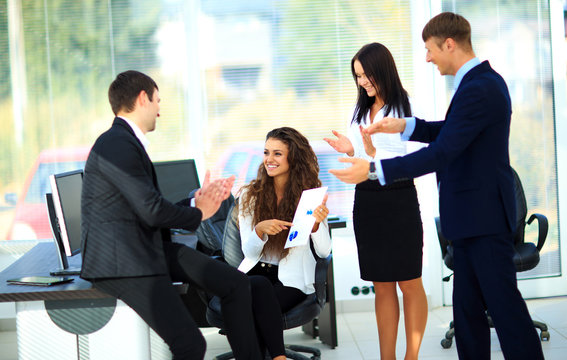 Young businesspeople clapping for female colleague after present