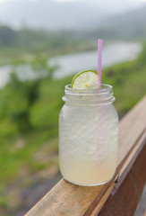 Lemonade with ice, lemon and lime slices in a jar with mountain