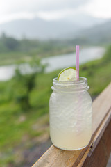 Lemonade with ice, lemon and lime slices in a jar with mountain