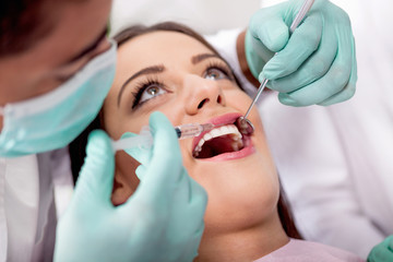 Dentist give syringe anesthetize  to his patient