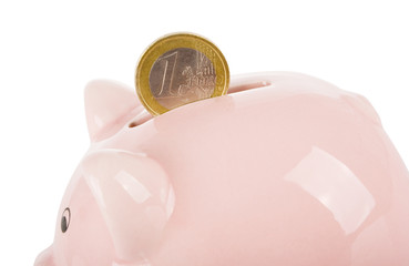 Hand putting one euro coin into piggy bank isolated on white