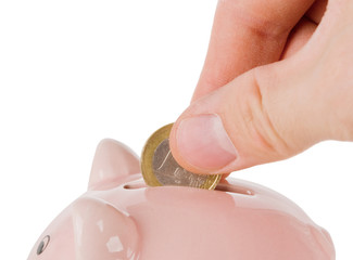 Hand putting one euro coin into piggy bank isolated on white