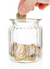 Hand putting one euro coin into money jar isolated on white