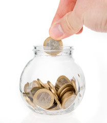 Hand putting one euro coin into money jar isolated on white