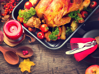 Thanksgiving dinner table served with turkey, decorated with bright autumn leaves