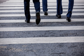 Pedestrian in business suits crossing on the road, feet rushing through the zebra traffic walk way