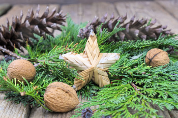 Christmas star made of straw on green pine needles with Walnuts