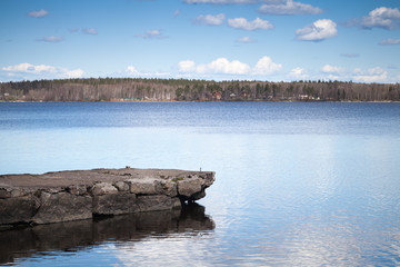 Still lake coastal landscape with old stone pier