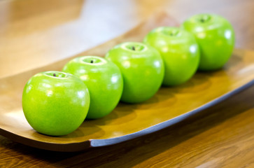 Plastic green apples on plate.