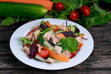 Tuna salad with Spinach, rocket, red ruby chard, tomatoes, cucumbers, carrot, red onion,  on old wooden table