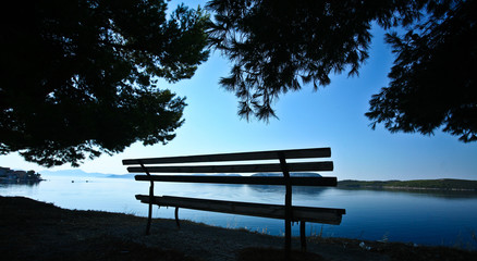 Trees and bench at the coast line in   Peloponese in Greece