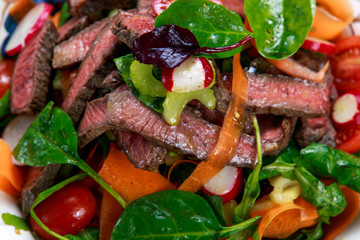 Spicy Beef Slices Meat Salad with Carrots, Tomatoes, Cucumber, Parsley and Salad leaves Spinach, rocket, red ruby chard