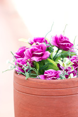 Colorful artificial flowers in clay pot.