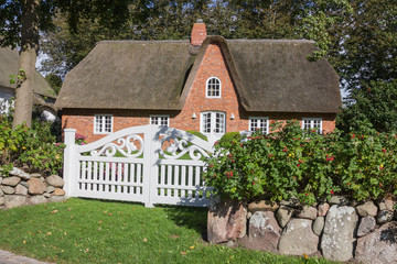 Reetdachhaus mit Friesenmauer und weißem Tor