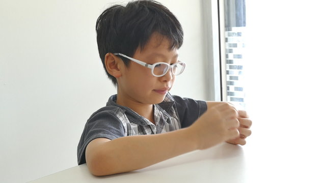 Young Asian boy wipes his snot by tissue paper 
