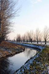 small river in wintertime at Havelland (Brandenburg, Germany). Along a path growing willow tries.