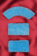 Labels made of jeans lying on the red silk