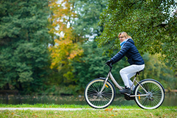 Fototapeta premium Urban biking - woman riding bike in city park 