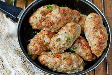Minced meat kebab in a frying pan, top view