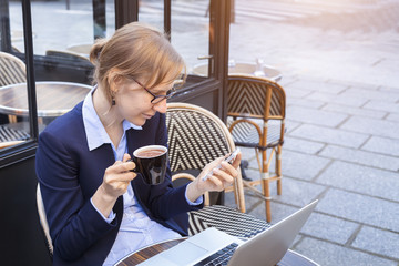 Young happy business woman using smartphone and laptop at lunch