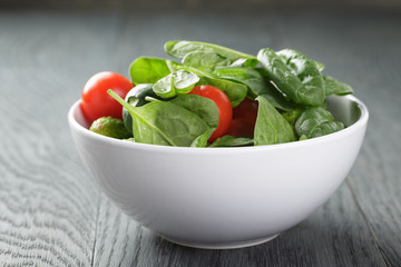 tomatoes and cucumbers in bowl on wood table