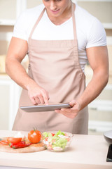 Tough-looking guy in the kitchen using his tablet.