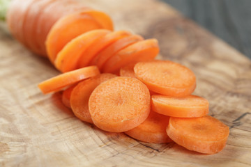 sliced organic carrot on olive wood cutting board