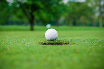 golf ball on lip of cup.  Golf ball and hole