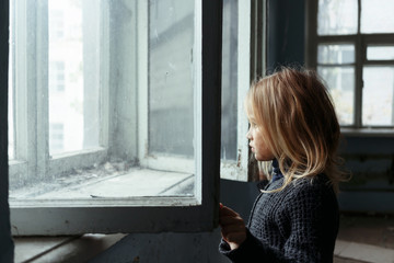 Fototapeta na wymiar Depressed poot girl standing near window 