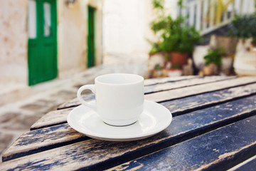 A cup of coffee on table with Mediterranean town at the background