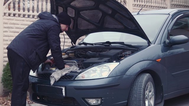 the man checks the engine in a car