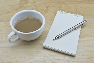 Coffee cup with pencil and notebook on table