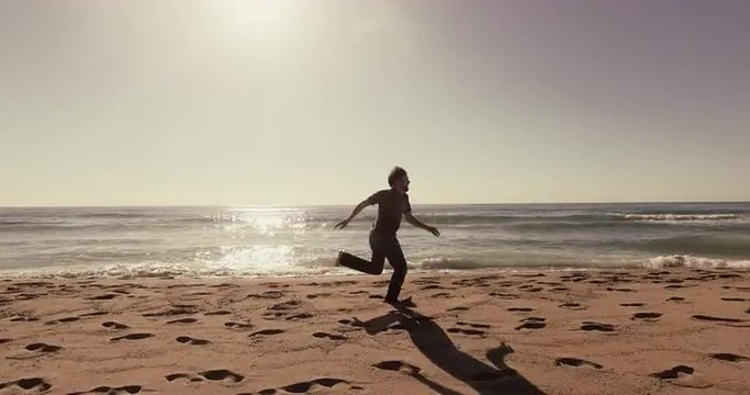 Man running and escaping on beach at sunset aerial footage