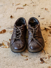 Naklejka premium Old and dirty men brown leather shoes with dry leaves on concret
